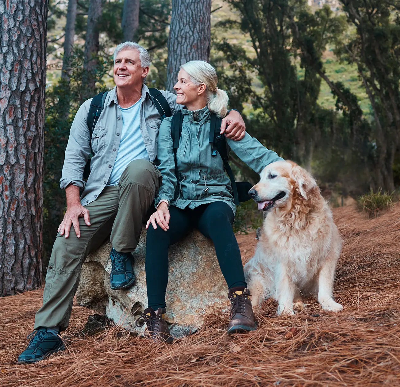 Couples personnes âgées faisant de la randonnée avec leur chien en forêt